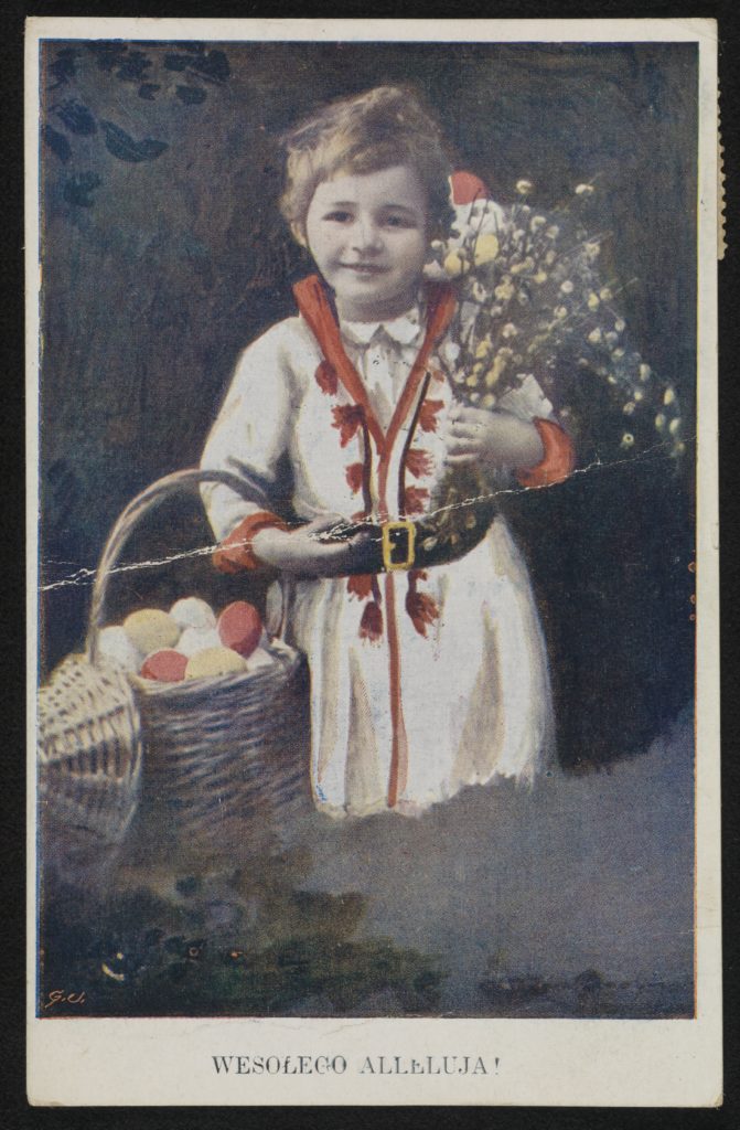 Uśmiechnięte dziecko w białym stroju trzyma zawieszony na zgiętym przedramieniu koszyk z kolorowymi jajkami, a w drugiej ręce trzyma naręcze polnych kwiatów.