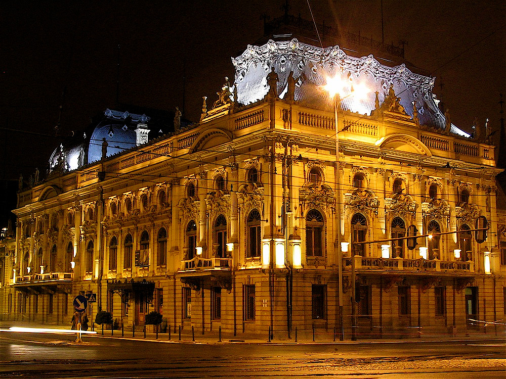 Nocne ujęcie na oświetlony eklektyczny pałac z wysokimi mansardowymi dachami