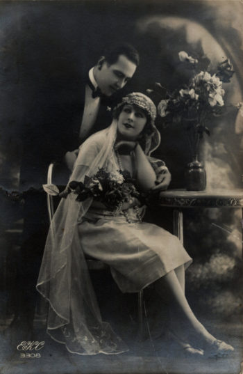 Fotografia ślubna, panna młoda siedząca oparta o stół i pochylający się nad nią pan młody.